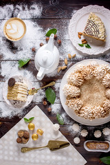 Beautifully decorated dessert table where the cake with meringue on a dark wooden table. Arrangement of delicious sweets