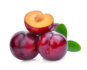 whole and half of cherry red plum with green leaves isolated on white background