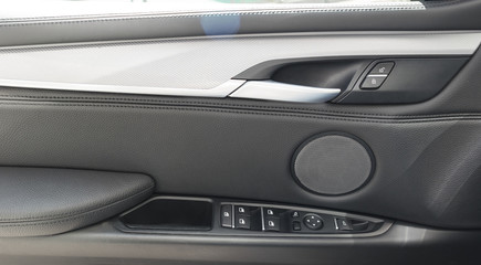 Car door handle inside the luxury modern car with black leather and switch button control modern car interior details