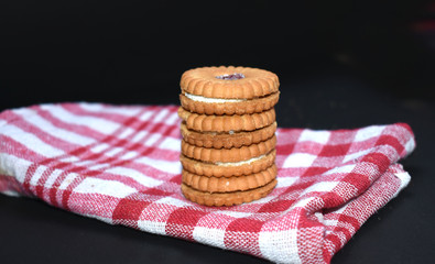 Biscuits filled with jam with chocolate gems filled with cream on black background