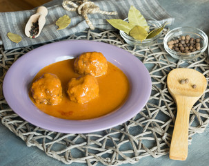 Meat balls of beef in tomato sauce served on a purple plate. As an addition to pasta