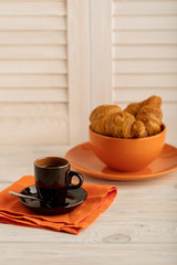 Coffee with croissants on a light wooden background.
