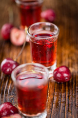 Cherry Liqueur on wooden background; selective focus