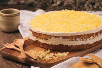 Tasty homemade cheesecake with cheese and wooden spoon on wood table