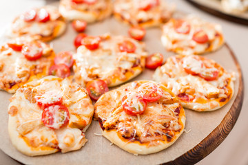 a lot of mini pizza, on wood plate. catering buffet. soft focus