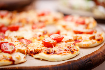a lot of mini pizza, on wood plate. catering buffet. soft focus