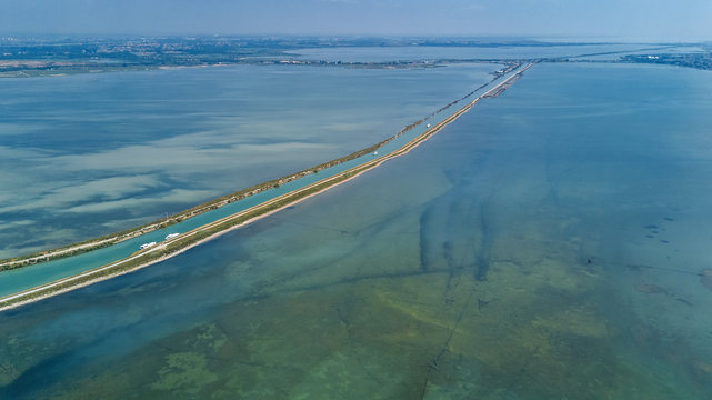 Aerial view of boats in canal in lagoon of Mediterranean sea Etang de Thau water from above, travel by barge in South France
