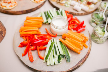 Fresh cucumber, carrot, red sweet paprika sliced in stripes on an olive wood cutting board