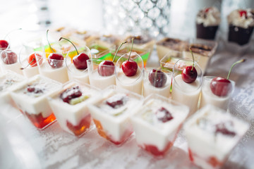 The cup of jellies  with cherries stand on the banquet table
