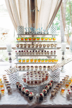 The different cakes,tiramisue and cups of jellies stand on the banquet table