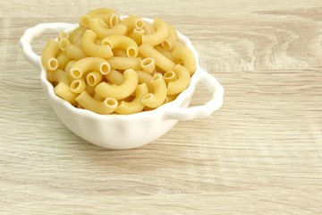 DRIED PASTA
Dried pasta in a white bowl on the wood table.