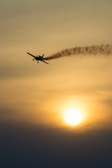 Plane with smoke trail at sunset