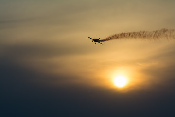 Plane with smoke trail at sunset