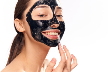 Beautiful young woman on white isolated background, black coal cosmetic face mask for face