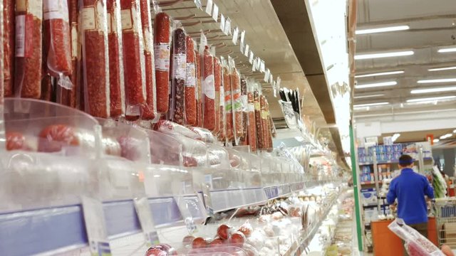 woman buys choosing a sausage in supermarket store