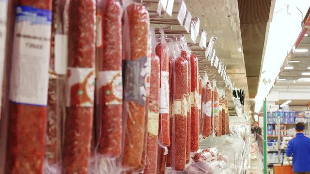 woman buys choosing a sausage in supermarket store