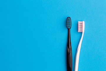 Black, pink toothbrushes on blue