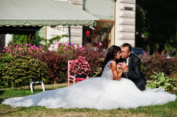Fantastic wedding couple sitting on the grass in a stunning garden.