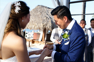 Groom puts a ring on bride's finger standing on the beach