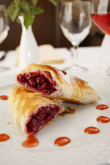 Cherry pie slice arranged on a plate, Wineglass in background, Traditional dessert in elegant setting, Selective focus with soft light