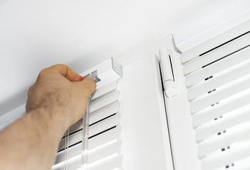 Man installing venetian blinds on windows.