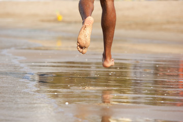 Man running barefoot along beach