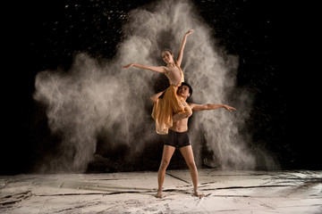 Attractive couple ballet dancer with white powder in the air