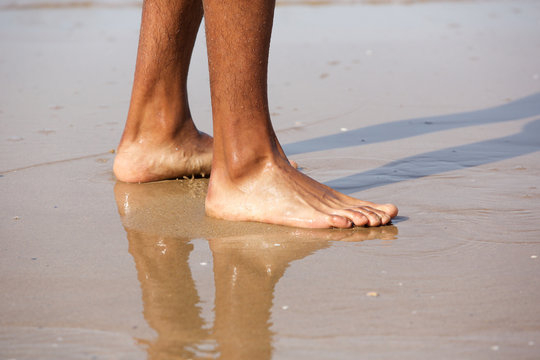 Young man standing with bare feet on beach