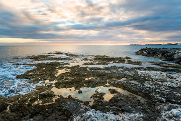 Tropical sunset with ocean and corals on foreground