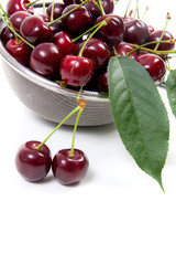 Steel colander with red sweet cherry isolated on a white background..