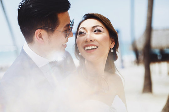 Bride looks over her shoulder at smiling groom in sunglasses