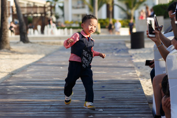 Little boy in black suit walks with black heart on his neck
