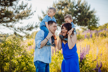 Parents hold their little sons on the shoulders standing on the field of lavander