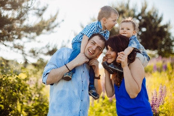 Parents hold their little sons on the shoulders standing on the field of lavander