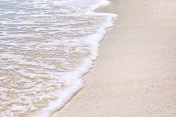 Warm sand and sea waves on beach at resort, closeup