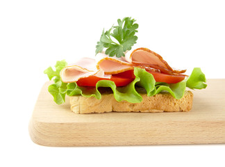 Toast,lettuce,tomato,cold cuts on cutting board on white