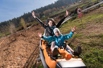 Obraz premium mother and son enjoys driving on alpine coaster