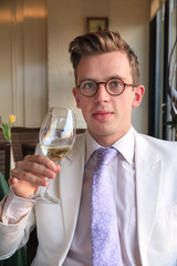 Beautiful and well dressed young man enjoying the tasting of a white wine in the afternoon in the Netherlands