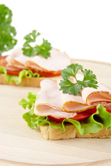 Toasts,lettuce,tomato,cold cuts on cutting board on white