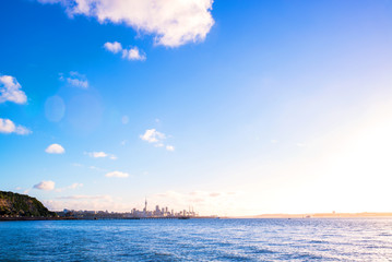 sunset on Auckland city’s skyline with the harbour, the ocean and some boats at the front