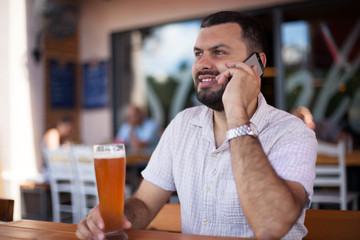 Handsome young man is using telephone in bar
