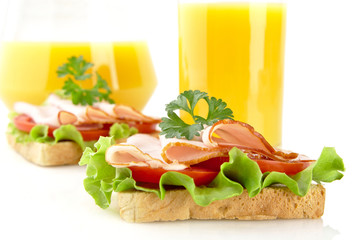 Toasts with cold cuts for lunchtime with orange juice on white