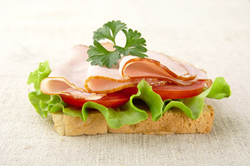 Slice of bread with lettuce,cold cuts on linen tablecloth
