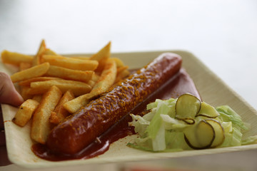 Currywurst mit Pommes und Salat auf Teller mit Ketchup 