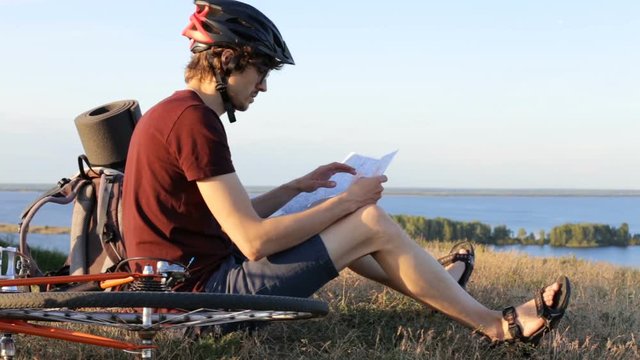 Cyclist with a map on top of the mountain