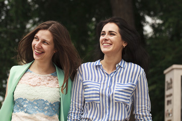 Obraz premium Two happy women walking in the summer park