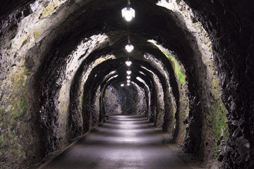 old rudimentary tunnel through a mountain in the Alps in Switzerland with very basic lighting