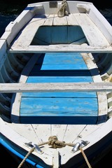 Fototapeta na wymiar blau weißes Fischerboot aus Holz am Meer schwimmend, Blick in ein kleines Holzboot, Erholung im Süden am Wasser