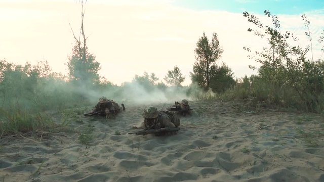 Group of armed military men crawling together near explosions on field in smoke.