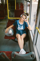 Woman with disco ball and headphones on a bus. 